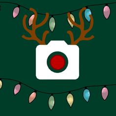 a camera with christmas lights hanging from it's sides on a dark green background