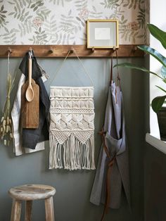 a wall hanging with wooden spoons and other items on it next to a potted plant