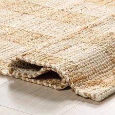 a close up of a rug on the floor with white tiles and wood floors in the background