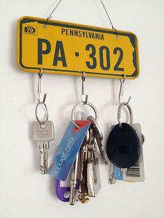 several keys hanging from hooks on a wall with a sign that says pa - 302