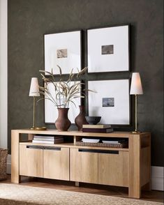 a living room with pictures on the wall and two vases in front of it