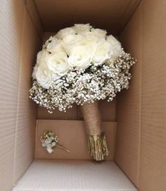 a bouquet of white roses and baby's breath in a cardboard box