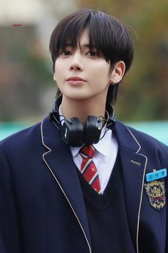 a young man with headphones on his ears wearing a school uniform and looking off to the side