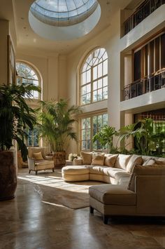 a living room filled with lots of furniture next to tall windows and potted plants