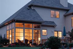 a large house lit up at night with lights on the windows and plants in the front yard