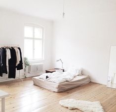 an unmade bed sitting on top of a hard wood floor next to a window