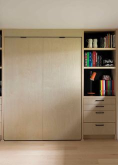 an empty room with bookshelves, cabinets and a lamp on the table in front of it