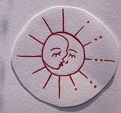 a sticker with a drawing of a sun and a face in red ink on white paper