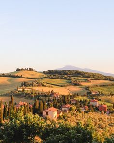 the countryside is full of trees and houses, with rolling hills in the back ground