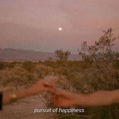 two hands reaching out towards each other in front of a desert landscape with the moon