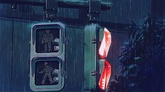 there are two traffic lights hanging from the side of a building with rain falling on them