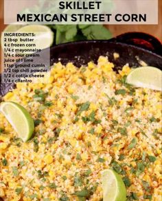 mexican street corn in a skillet with limes and cilantro on the side