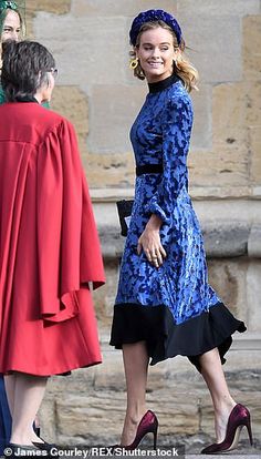 a woman in a blue dress and red coat is walking next to another woman with her hand on her hip