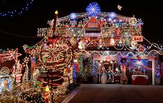 a house covered in christmas lights at night with lots of decorations on the front and side