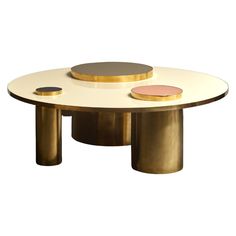 an oval coffee table with two circular brass bases and one pink disc on the top