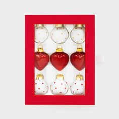 red and white christmas ornaments in a red box with gold trim around the edges, hanging on a wall