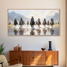 a group of people riding horses on the beach in front of a mountain range painting