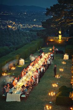 a long table is set with candles and people are sitting at the tables in front of them