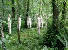 several white statues are standing in the woods