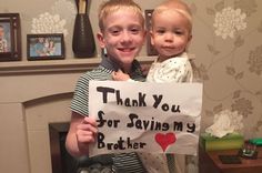 a young boy holding a sign that says thank you for saving my brother