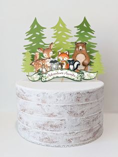 there is a cake that has animals on it and trees in the background with a banner