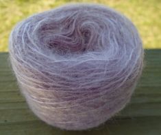 a purple ball of yarn sitting on top of a wooden table next to green grass