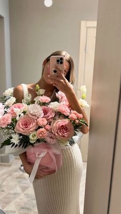 a woman taking a selfie while holding a bouquet of flowers