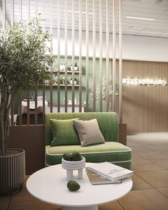 a green couch sitting next to a white table with a book on top of it