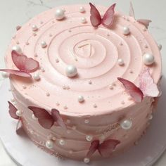 a pink cake decorated with butterflies and pearls