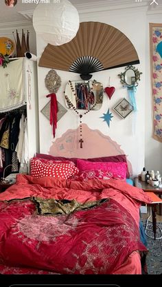 a bed with red comforter and pillows in a room filled with pictures on the wall