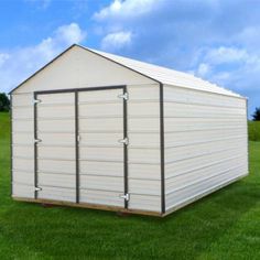 a white shed sitting on top of a lush green field next to a blue sky