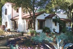 a white house surrounded by trees and plants