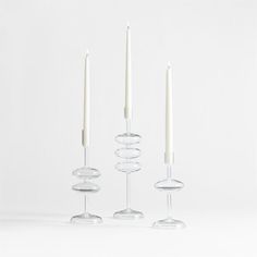 three glass candlesticks with one candle in the middle