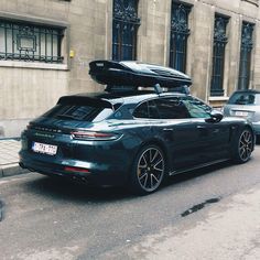 a black car parked on the side of a street with luggage strapped to it's roof