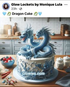 a blue dragon cake sitting on top of a counter next to a bowl of fruit