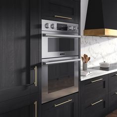 a kitchen with black cabinets and gold trimmings on the oven door, stove hood, and counter tops