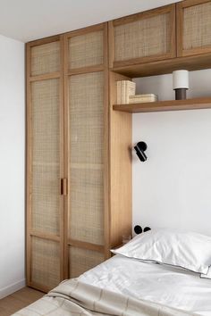 a bed sitting under a wooden shelf next to a white wall