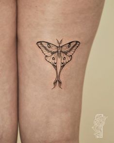 a small butterfly tattoo on the thigh is shown in black and grey ink, with an intricate