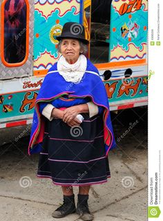 an old woman standing in front of a brightly colored bus with her hands on her hips