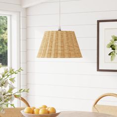 a bowl of oranges sitting on top of a wooden table next to a window