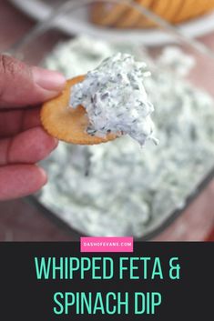 a hand holding a cracker with whipped feta and spinach dip