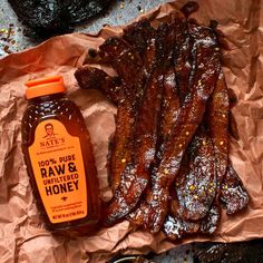 barbecue ribs and honey sit on wax paper next to the bbq's sauce