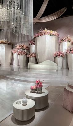 a room filled with lots of white vases covered in pink flowers and hanging chandeliers