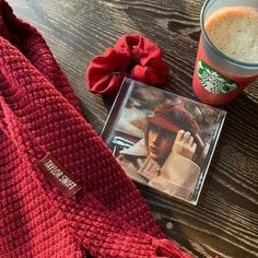 a cup of coffee and a book on a wooden table next to a red sweater