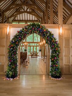 an archway decorated with flowers and greenery in the middle of a room filled with wooden floors