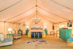 a large tent with a bed, dressers and other furniture in the room inside