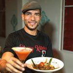 a man is holding a bowl of food and a drink