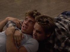 two men laying on the ground hugging each other