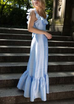 a woman in a blue dress standing on some steps