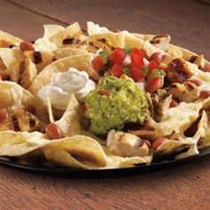 nachos on a plate with guacamole, tomatoes and other toppings